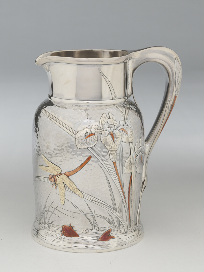 Shiny silver pitcher with pond design featuring reeds, dragonfly