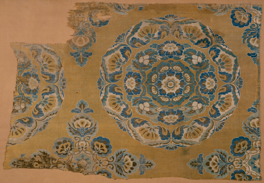 Cloth fragment of dress, blue and brown floral design in circular patterns.