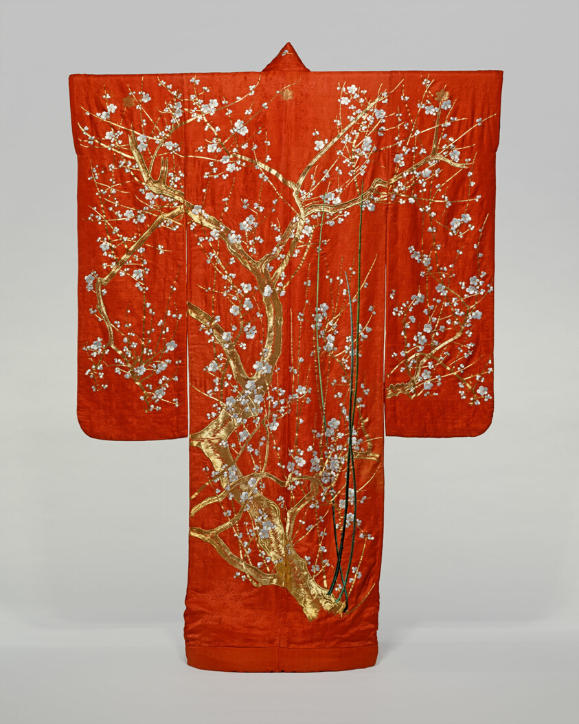 Red long sleeve garment embroidered with a large gold tree with white blossoms.
