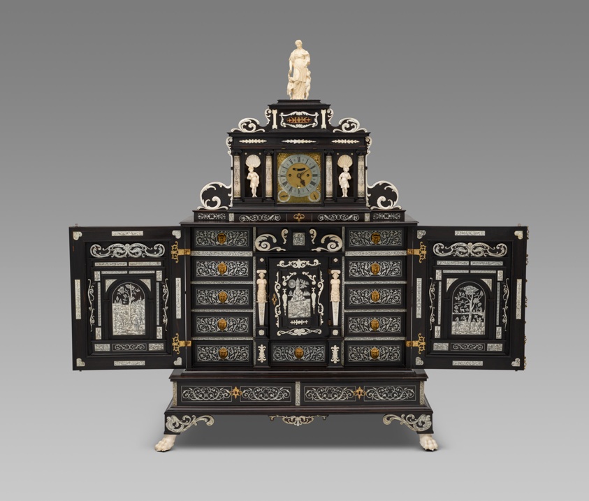 Large ebony cabinet with white designs, ivory figures, clock.