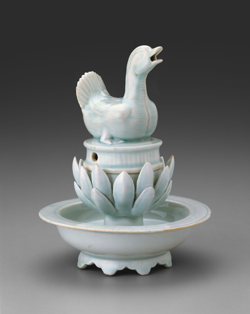 Porcelain sculpture with pale-blue glaze, shape of a duck atop a lotus flower.