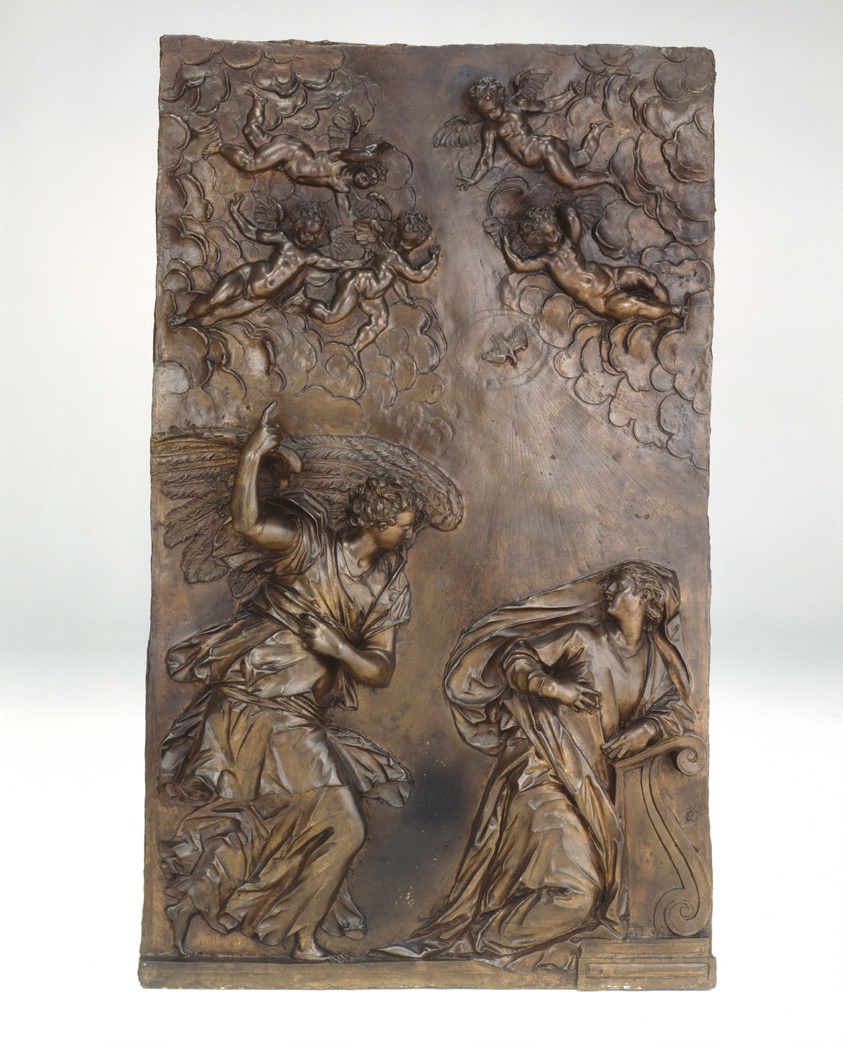 Relief sculpture of angel confronting Virgin Mary. Cherubs and dove in sky.
