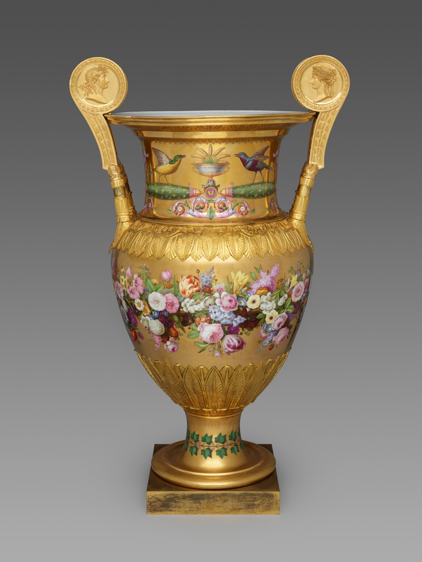Gold porcelain vase with flowers, birds, profile heads on handles.