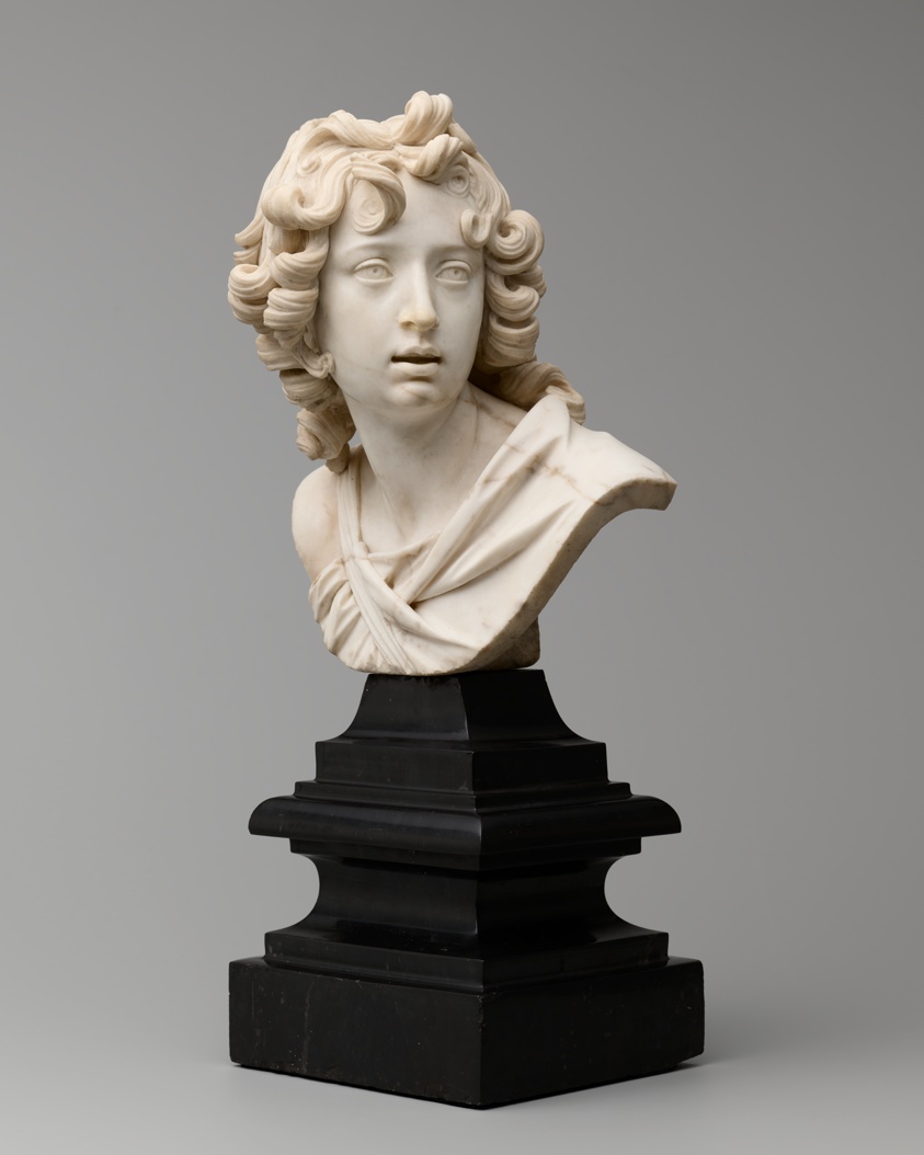 Bust of young boy with large eyes and long curly hair, looking to his side.