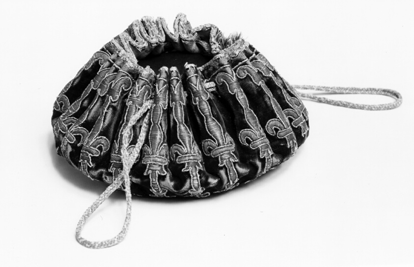 A work made of silk, broken warp-chevron twill weave with supplementary pile warps forming cut solid pile; embroidered with silk and gilt-metal-strip-wrapped silk in laid work, couching, and padded couching; over leather; edged with silk, plain weave tape; drawstring of silk, oblique interlacing.